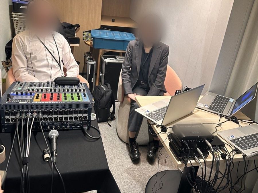 Laptops and audio equipment on two tables, with two Oyraa staff checking the sound (faces blurred)