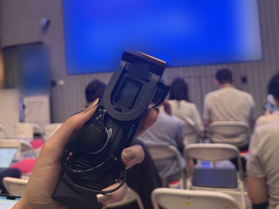 A guest holding a receiver and earphone, with the screen and audience in the background